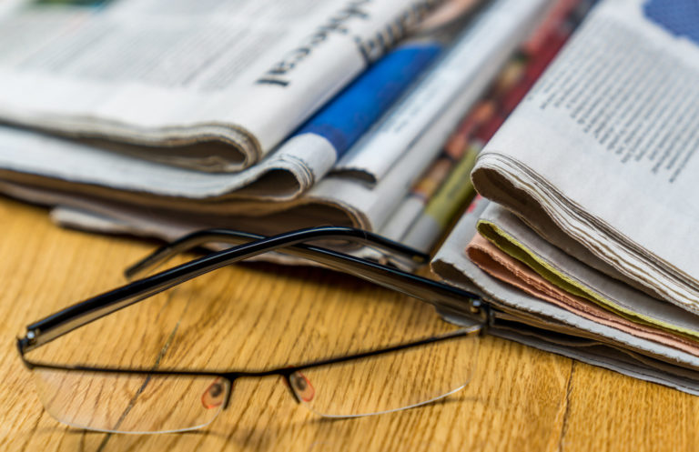 Glasses beside a pile of newspaper