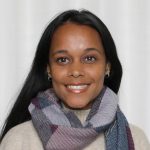 Brown woman with a smile, multicolour scarf over an off white sweater