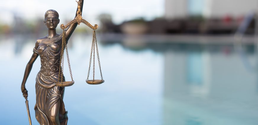 Statue of the justice holding a scale in front of a large body of water
