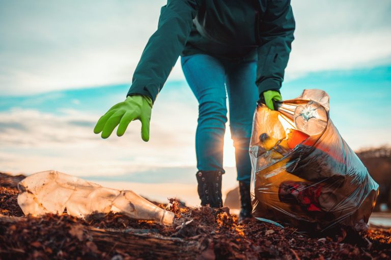 A volunteer collects garbage on a muddy beach. Close-up.