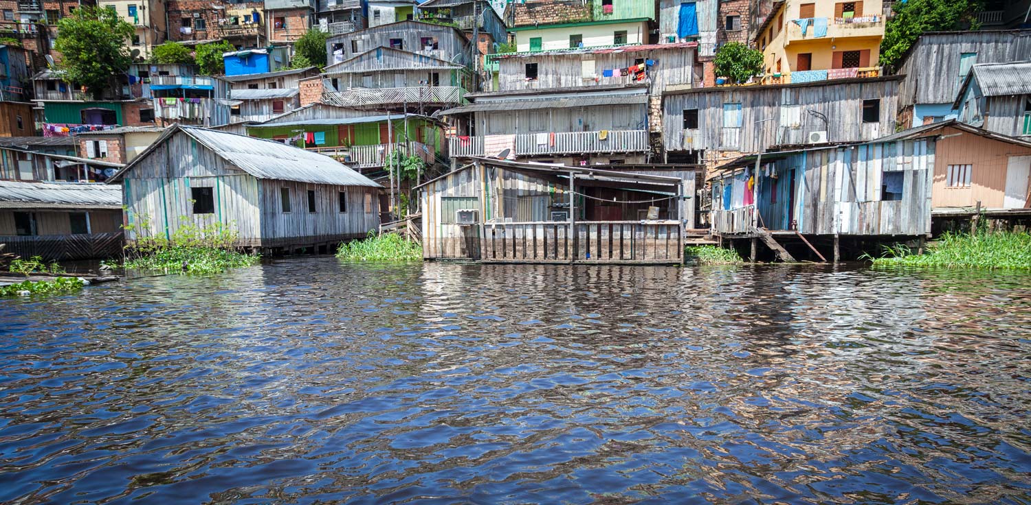 Wooden houses on a hillside, coming right down to the edge of a river.