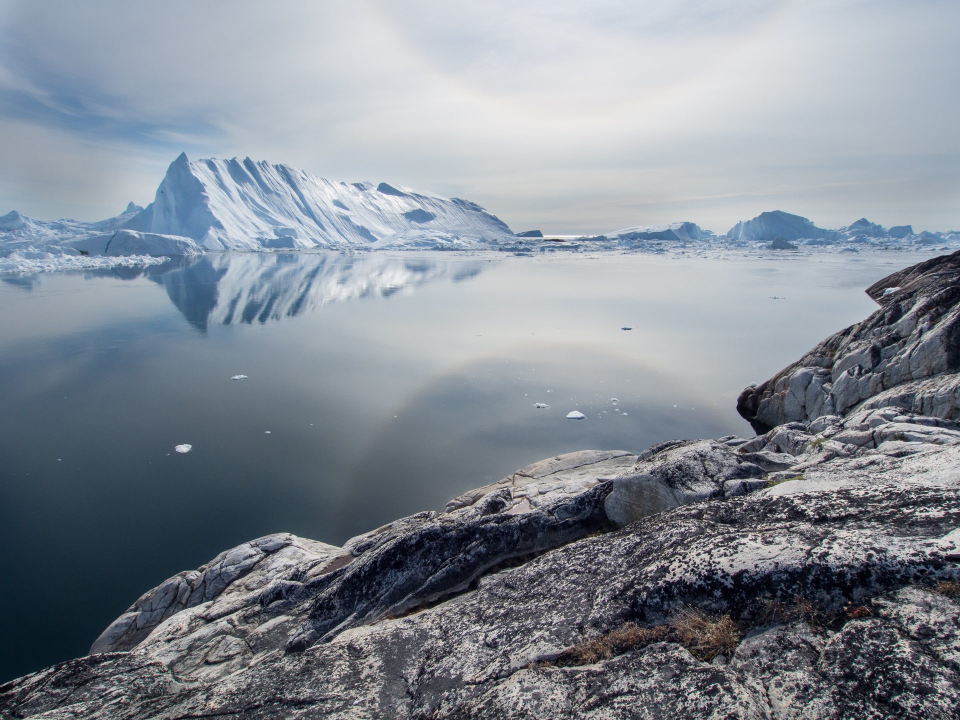 Glacier floating on the horizon. A block of grey rock in the foreground.