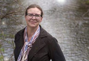 Dr Lara Fowler, looking up to the camera. A blurry river in the background