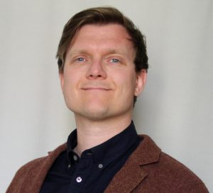 Man with a brown suit and a smiling face