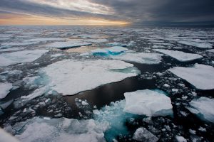 Sea ice melting, with sun setting on the horizon