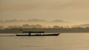 Boat sailing along the Mekon River in a misty sunrise