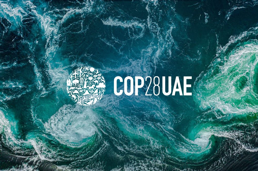 Swirly water from above, with turquoise, blue and white shades. COP28 UAE logo