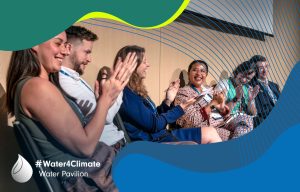 Young professional debate panel sitting on stage at World Water Week 2023, clapping their hands and laughing