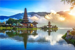 Indonesian pagods reflecting on water with mountains in the background