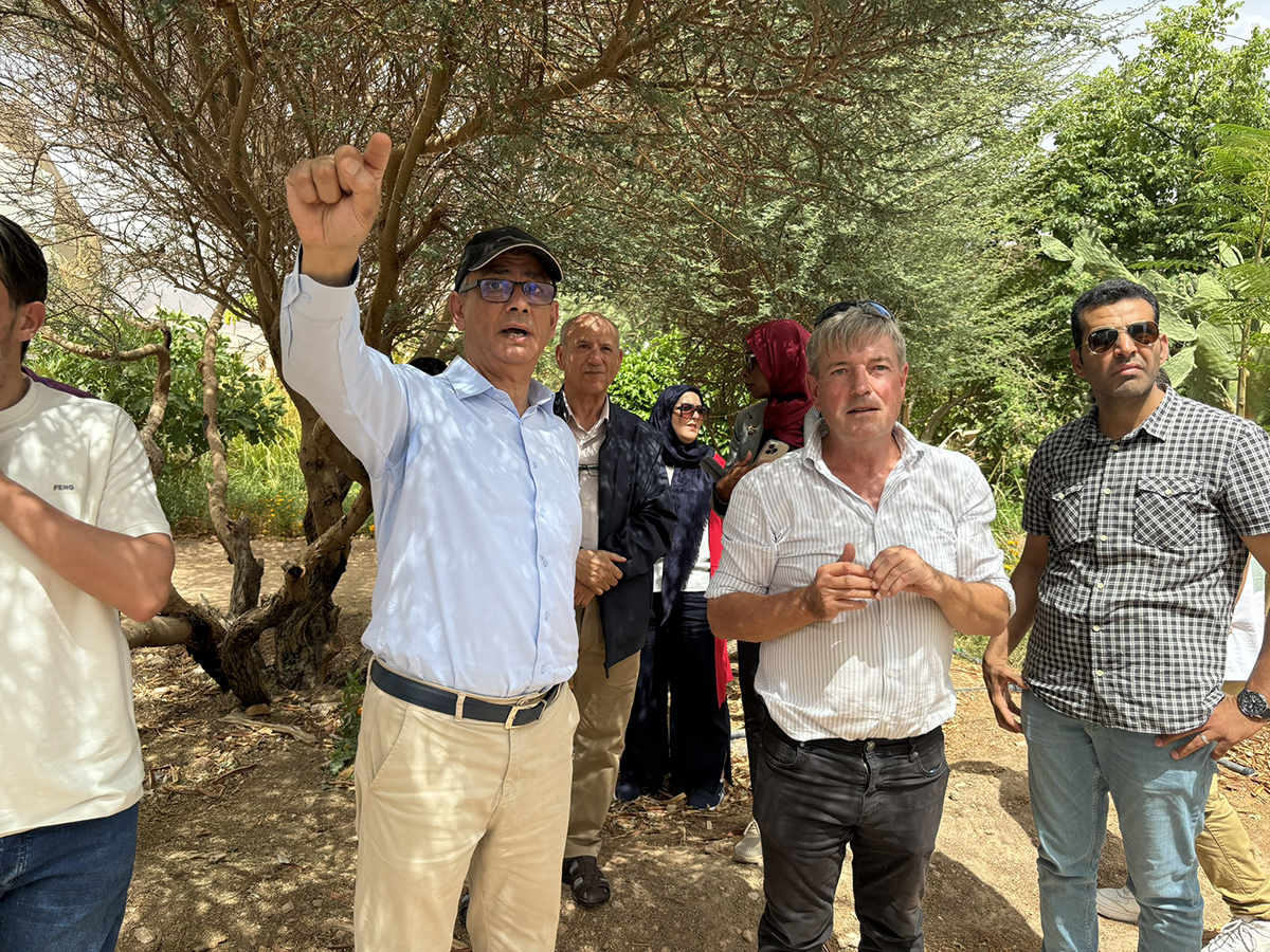 SIWI's Moez Allaoui standing outside, pointing something behind the camera to a group of people standing beside him.